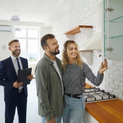 Realtor with customers checking apartmnet. Couple examines furniture in kitchen while inspecting house with real estate agent